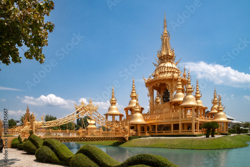 Golden Ganesha Shrine at Wat Rong Khun the White Temple, Ornate Traditional Thai Architecture under Blue Sky with Clouds, Chiang Rai, Thailand