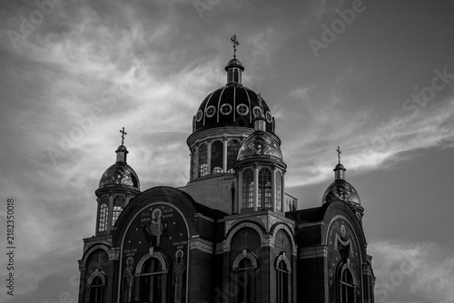 Quadro su tela Ornate church beneath dramatic clouds in black and white
