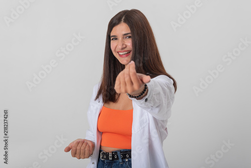 Fotografie Smiling young woman extending her hand and making an inviting come here gesture,