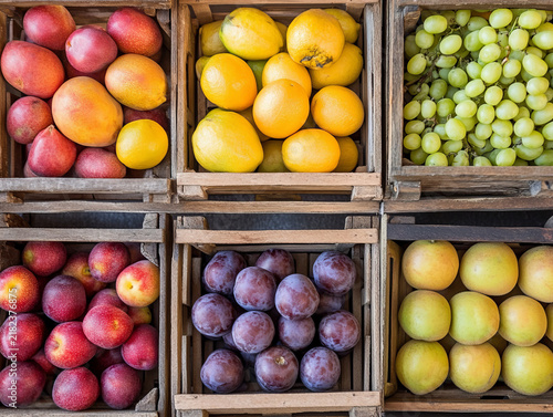 Assortment of fresh seasonal ripe fruits in wooden boxes market display
