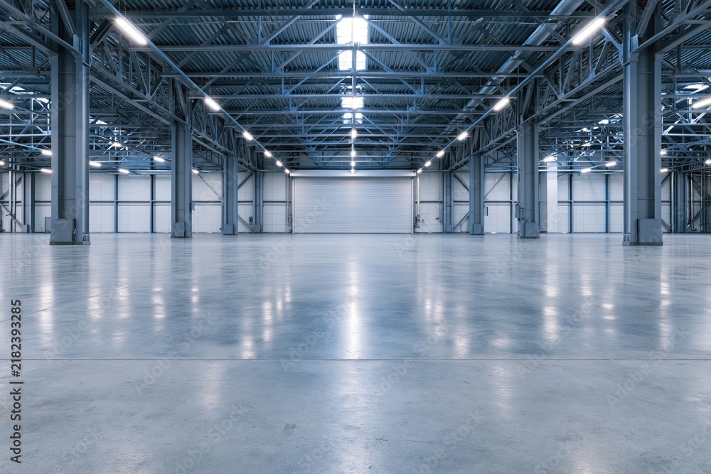Obraz premium The expansive empty warehouse interior with high steel framework and polished concrete floor