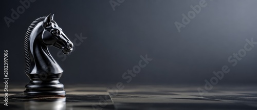 Strategic black chess knight on a marble board with dark background and copy space, symbolizing business strategy and banner format