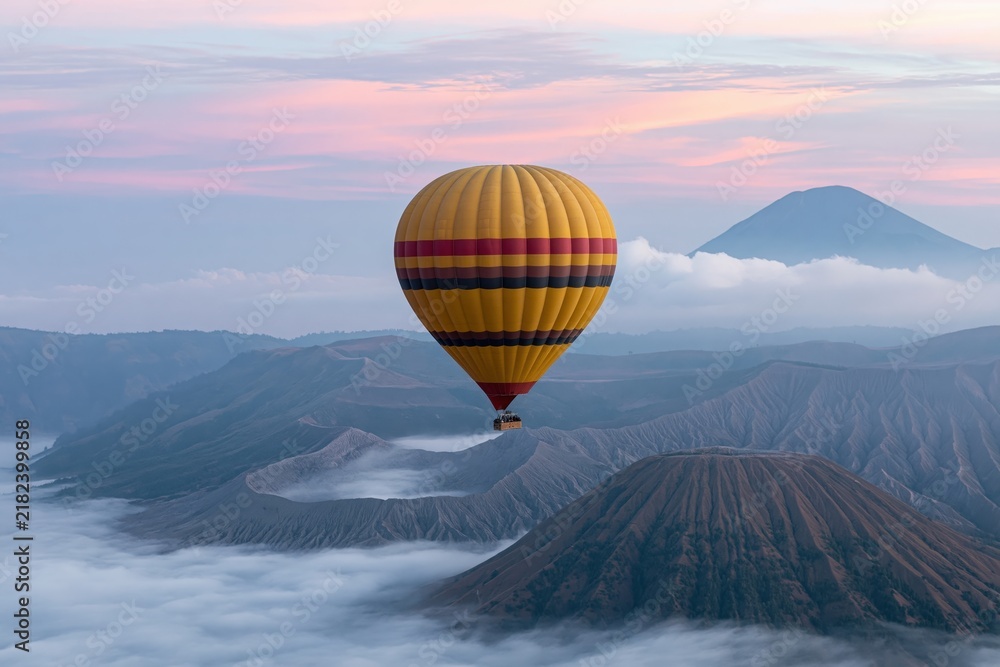 Obraz premium The Hot Air Balloon Above Misty Mountains During Sunrise in Clouds