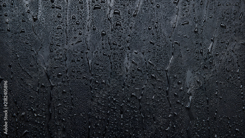 Dark slate background with water droplets, wet black stone texture, moody rain condensation on matte surface for product display