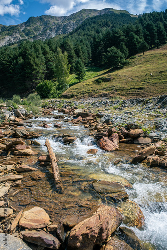 Senderismo por las montañas y valles del Valle de Aran en el Pririneo, caminando junto a un río alpino