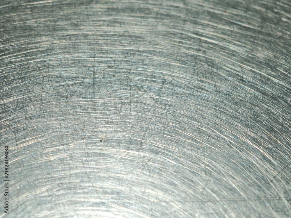 Fototapeta premium Scratches and circular swirl patterns on a worn stainless steel table top create an industrial metallic texture in a restaurant setting