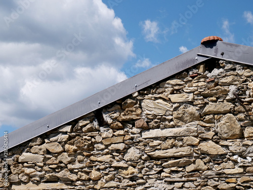 Dry-stone house with a roof featuring metal edging 