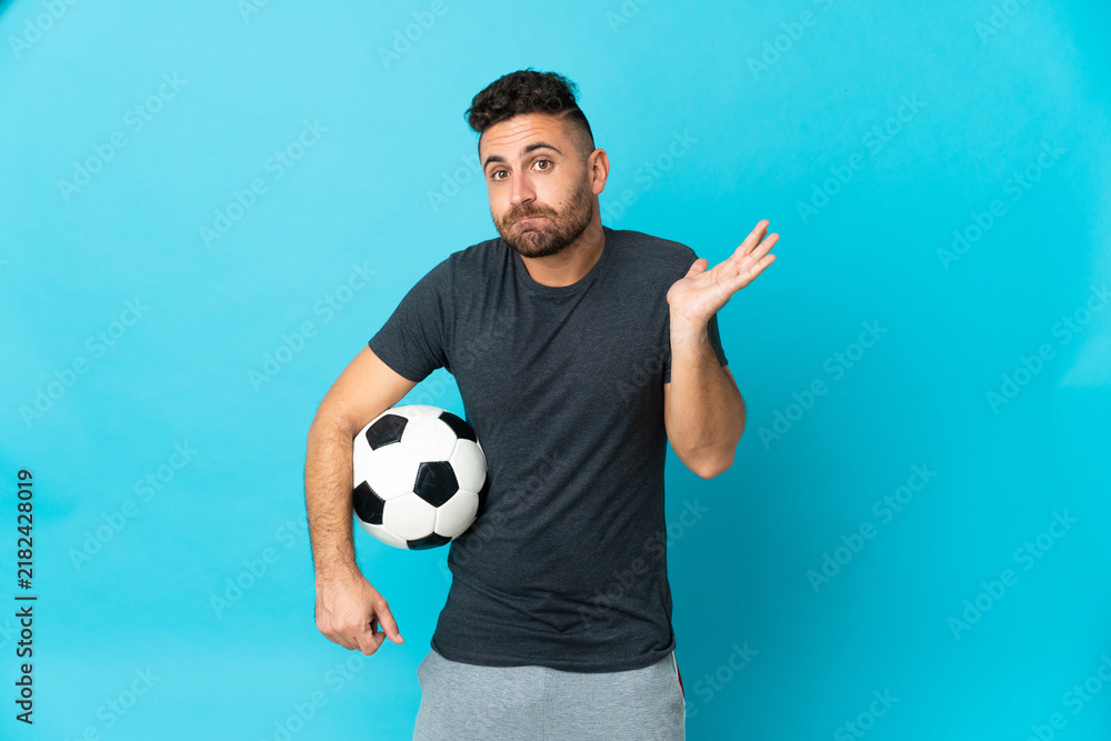 Obraz premium Football player isolated on blue background having doubts while raising hands