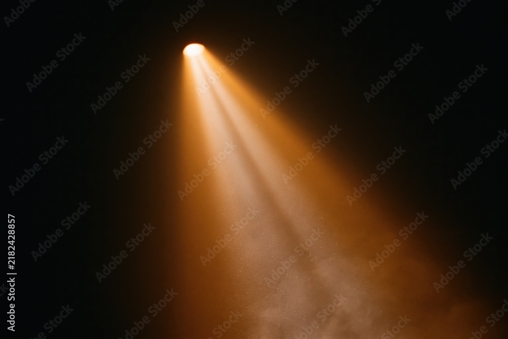 Obraz premium The Spotlight Casting Warm Amber Beams Across a Dark Theatrical Stage