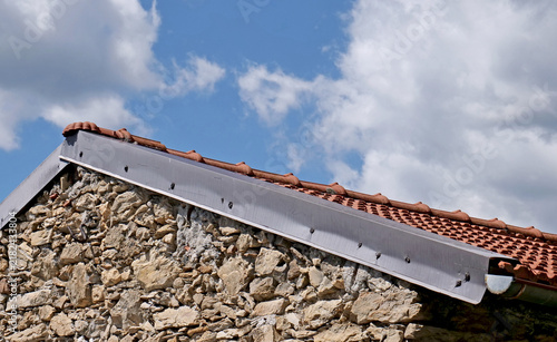 Mountain roof on a dry stone house, featuring ceramic tiles and a metal gutter closed at one end.