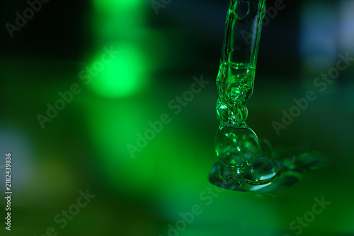 Konstfotografi Close-up of clear liquid droplets forming on a glass pipette with a blurred gree