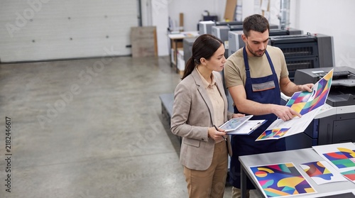 Professional and client evaluating color proof in print shop