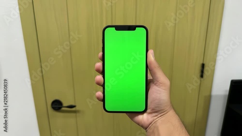 Hand holding modern smartphone with bright green chroma key screen in this high quality vertical motion video clip for editing