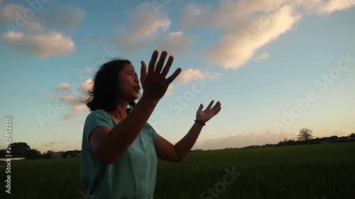 A woman standing in a field with her hands raised towards the sky at sunset. outdoor wellness activity