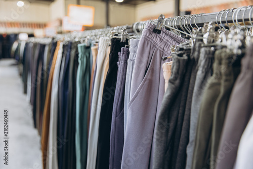 Clothing rack displaying various colors of sweatpants and casual trousers in a modern fashion store or retail shop