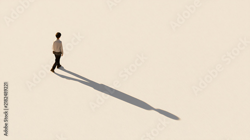 A solitary person walk across a vast empty white space with long shadow cast by bright light create minimalist artistic composition