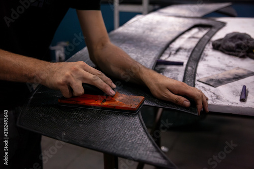 craftsman sands a car part with a sanding block