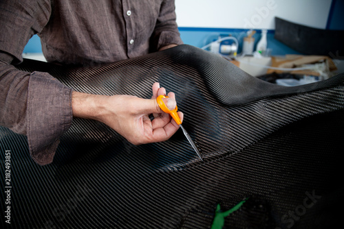 Close-up of a hand cutting fabric along the contour of a mold