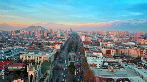 Aerial view of Santiago city downtown featuring busy traffic streets with Andes mountains in background at sunset.