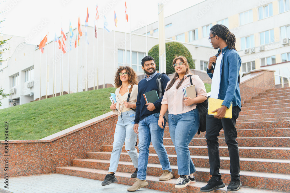 Obraz premium Diverse students walking down university stairs with books
