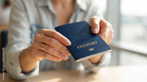 Woman holding blue passport for international travel identification and border security control check at airport check in counter