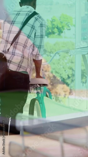 Animation of hands using tablet, over man arriving at creative office with bike