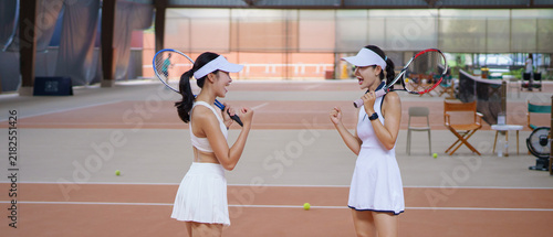 Obraz na płótnie Two Asian Women Tennis Players Celebrating a winning point together with Fist Pu