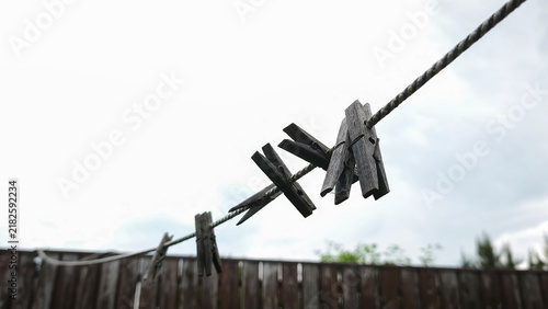 Foto Wooden clothespin hangs on thin clothesline rope outdoors