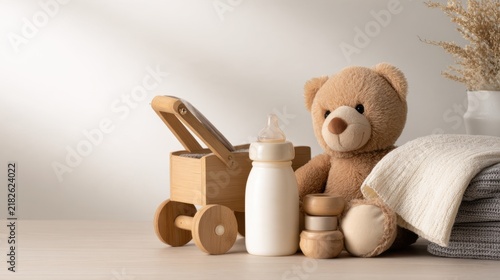 A cozy arrangement of a teddy bear, baby bottle, and wooden toy stroller on a minimalistic surface
