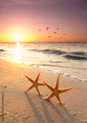 Romantic Autumn Sunset with starfishes on the Beach