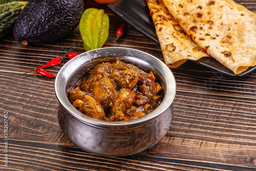 Bild auf Leinwand Rich chicken curry in metal bowl with naan bread, avocado, star fruit and red ch