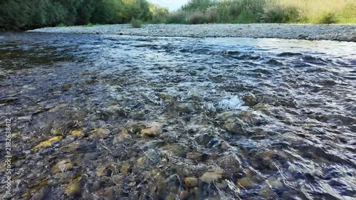 The flow of a clear, clean mountain river in the shallows, natural background