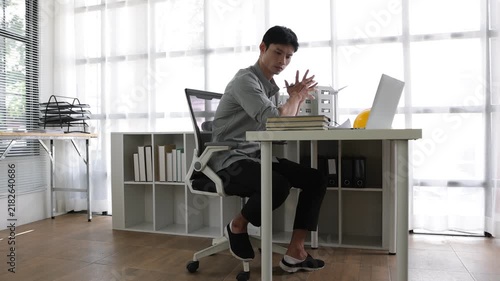 Stressed young asian engineer feeling tired at work.