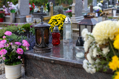 Foto Colorful flowers and candles on grave in cemetery