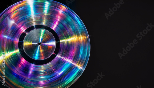 Holographic rainbow iridescent vinyl record disc on dark background synthwave and music retro futuristic concept