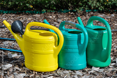 Threesome of colorful water cans in garden