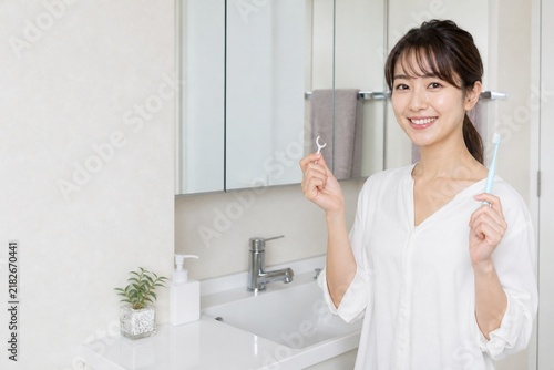 Naklejka 歯ブラシとフロスを持つ洗面所の日本人女性