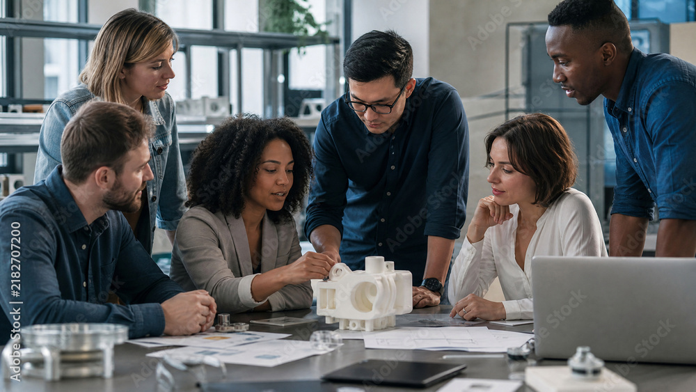 Obraz premium Diverse engineering team analyzing 3D printed prototype, creative designers collaborating in modern office, professional architects working on project