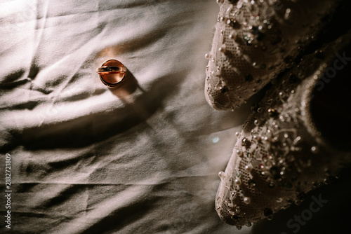 Foto Bridal shoes and wedding ring on white fabric