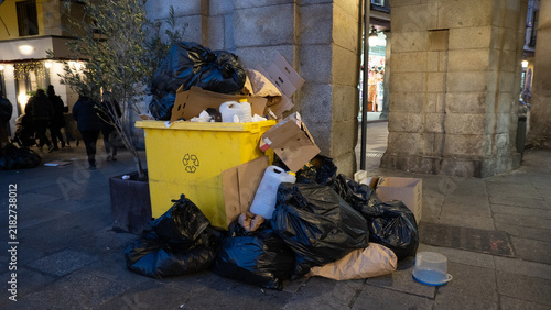 Принти на полотні Overflowing recycling bin with trash bags on city street