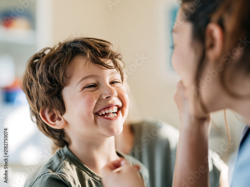 Happy child boy smiling brown hair casual clothing indoor sunlight joyful communication therapy session speech therapy stuttering fluency disorder learning interaction positive emotion childhood