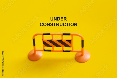 Under construction sign on yellow background for roadwork, building renovation, safety, and restricted access