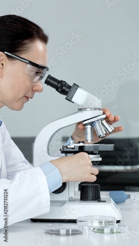 Obraz na plátně Female scientist looking into a microscope