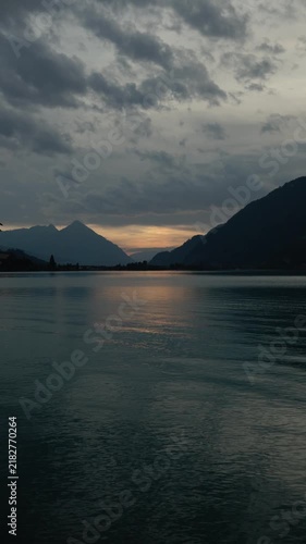 Beautiful sunset over a peaceful mountain lake surrounded by dramatic peaks and glowing evening sky.