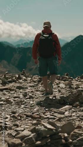 Solo hiker walking across a rocky alpine trail at Top of Tyrol, Austria, surrounded by dramatic mountain peaks at over 3,200 meters altitude in the Stubai Alps.