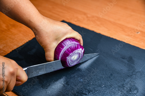 Woman cutting red onion on cutting board