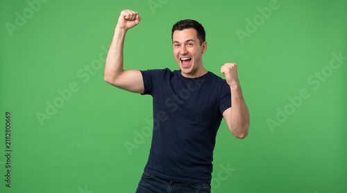 Excited man celebrating success with raised fists isolated on green screen background