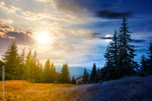 hill with coniferous forest on a meadow in mountains of Ukraine. day meet night. sun and moon over Synevyr national park landscape, Transcrpathia on autumn equinox. spruce trees under epic sky