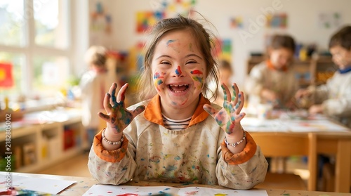 Happy girl with down syndrome showing her paint stained hands in a school art class