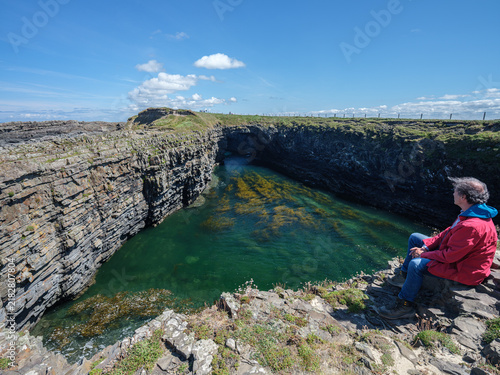 Quadro su tela Man sits alone, gazing at deep green sea pool